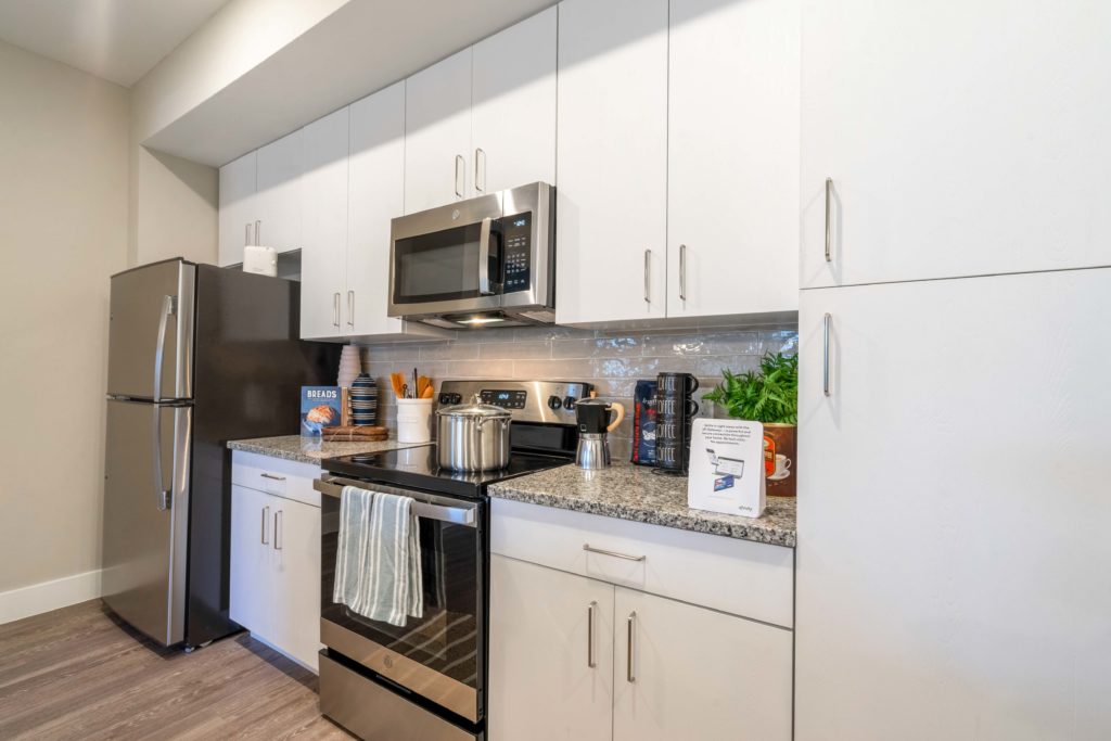Kitchen with stainless steel appliances, wood-style flooring, granite countertops, and designer lighting