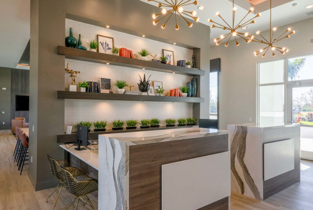 Reception desk with wood-style flooring, designer and natural lighting, table seating, and plant decor