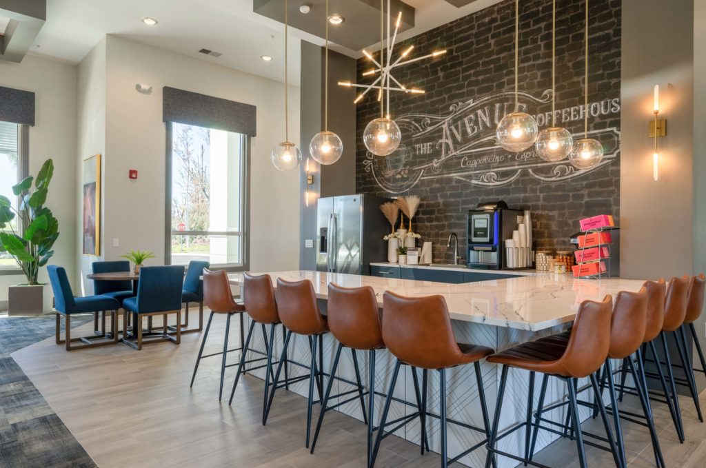 Interior clubhouse with designer and natural lighting, bar area with seating, granite countertops, and wood-style flooring