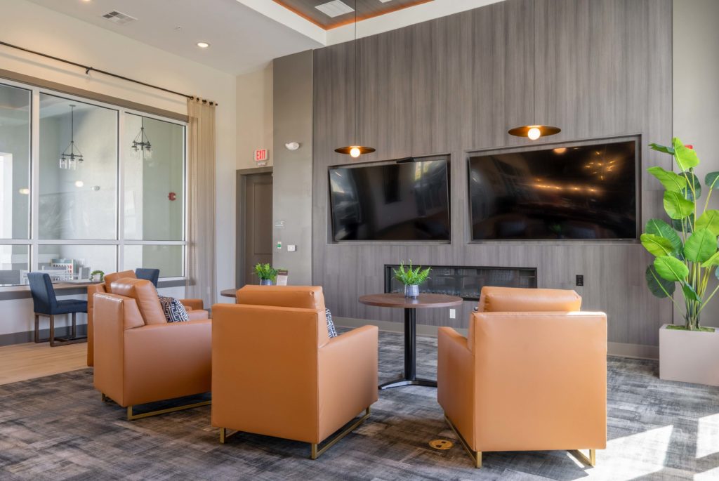 Interior clubhouse with designer and natural lighting, lounge seating, carpet flooring, fire pit, and TVs