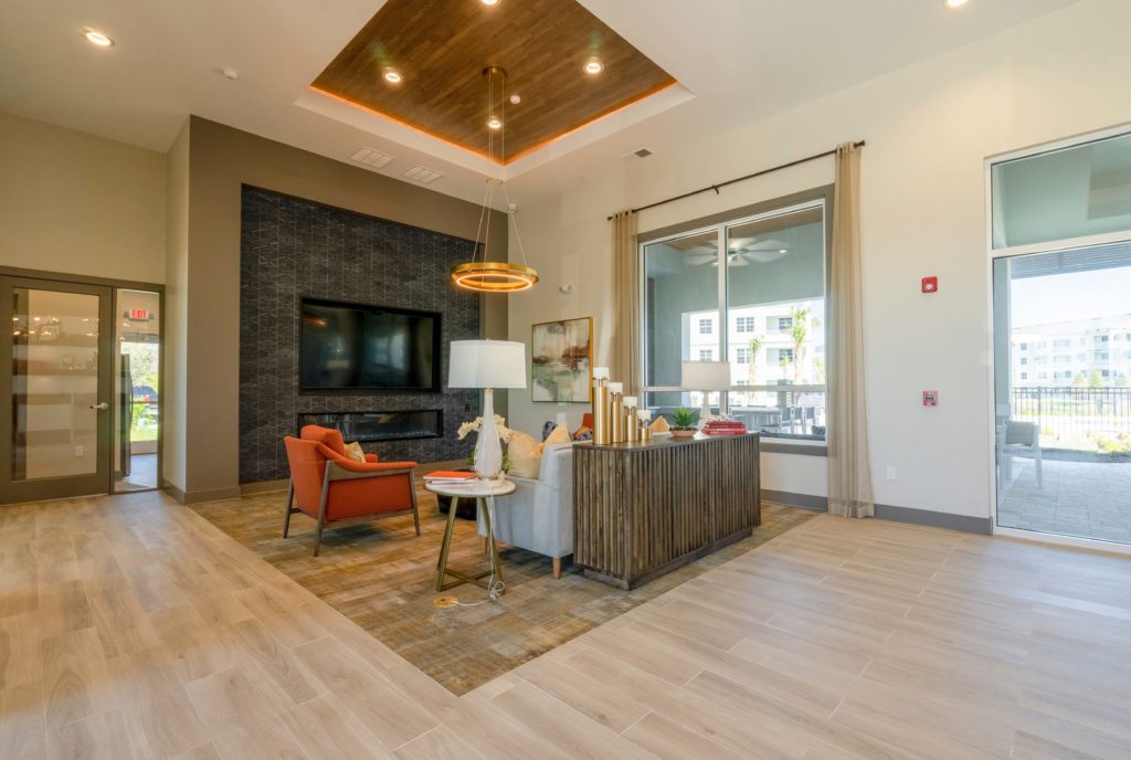 Clubhouse interior with wood-style flooring, designer lighting, lounge and couch seating, fire pit, and TV